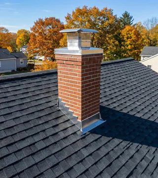 After: rebuilt red brick chimney with a stainless cap and new flashing on a clean shingle roof